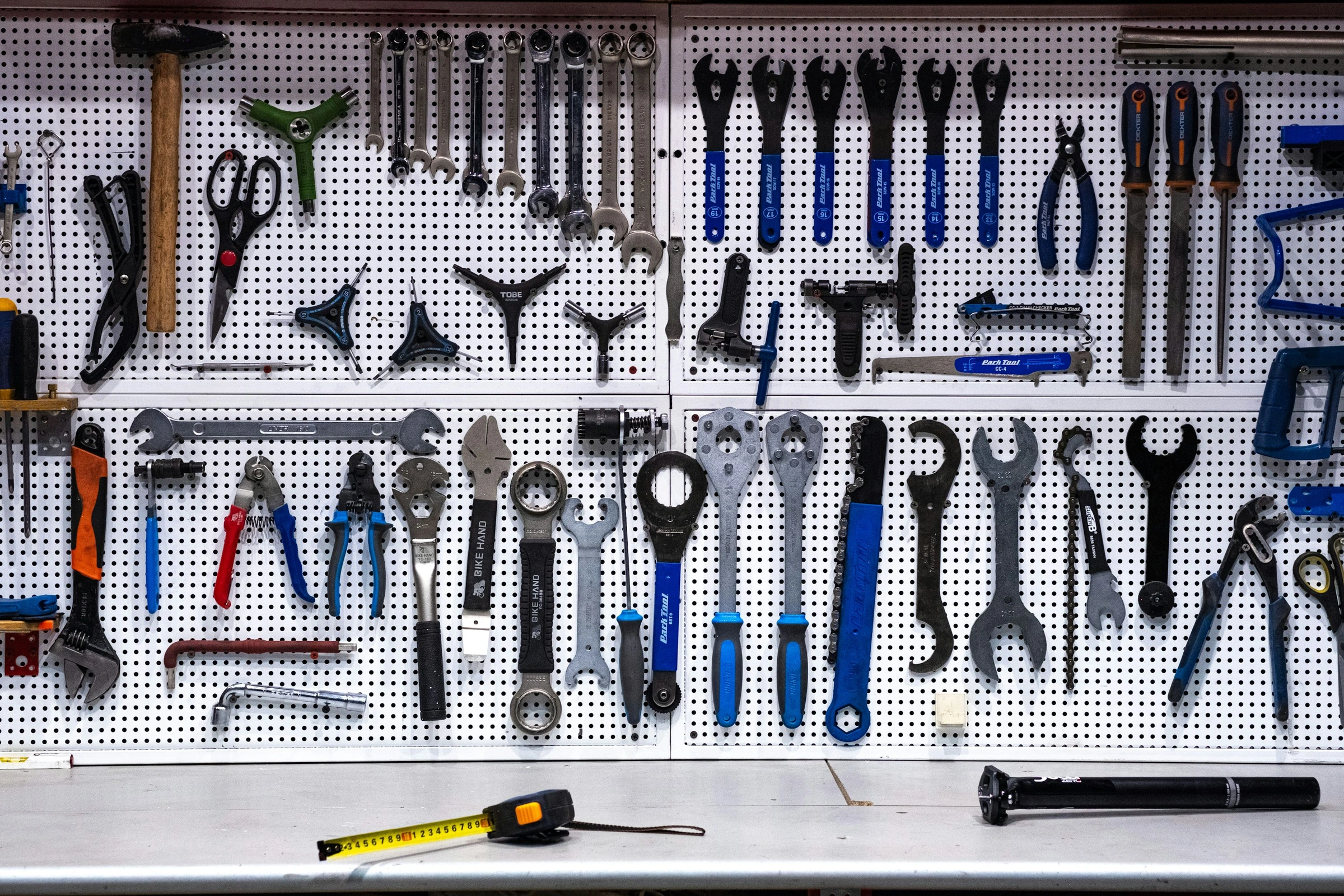 Wrenches, pliers and repair tools organized above a workshop bench